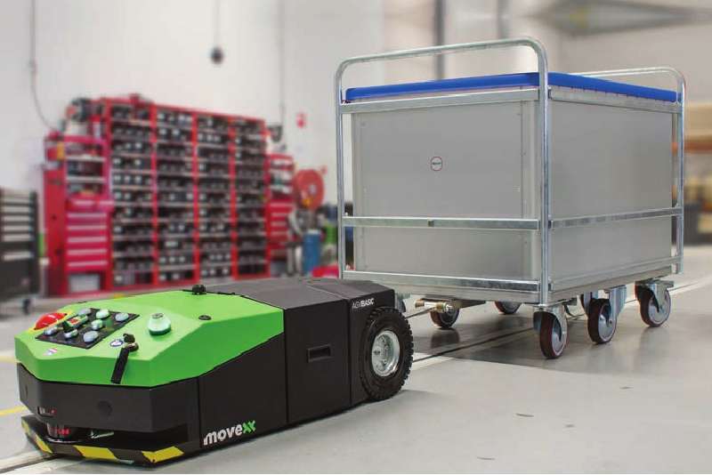 elektrický automaticky vedený tahač agv-basic veze přepravní vozík zapojený ojí po předem vyznačené trati při zásobování výroby, milkrun systém